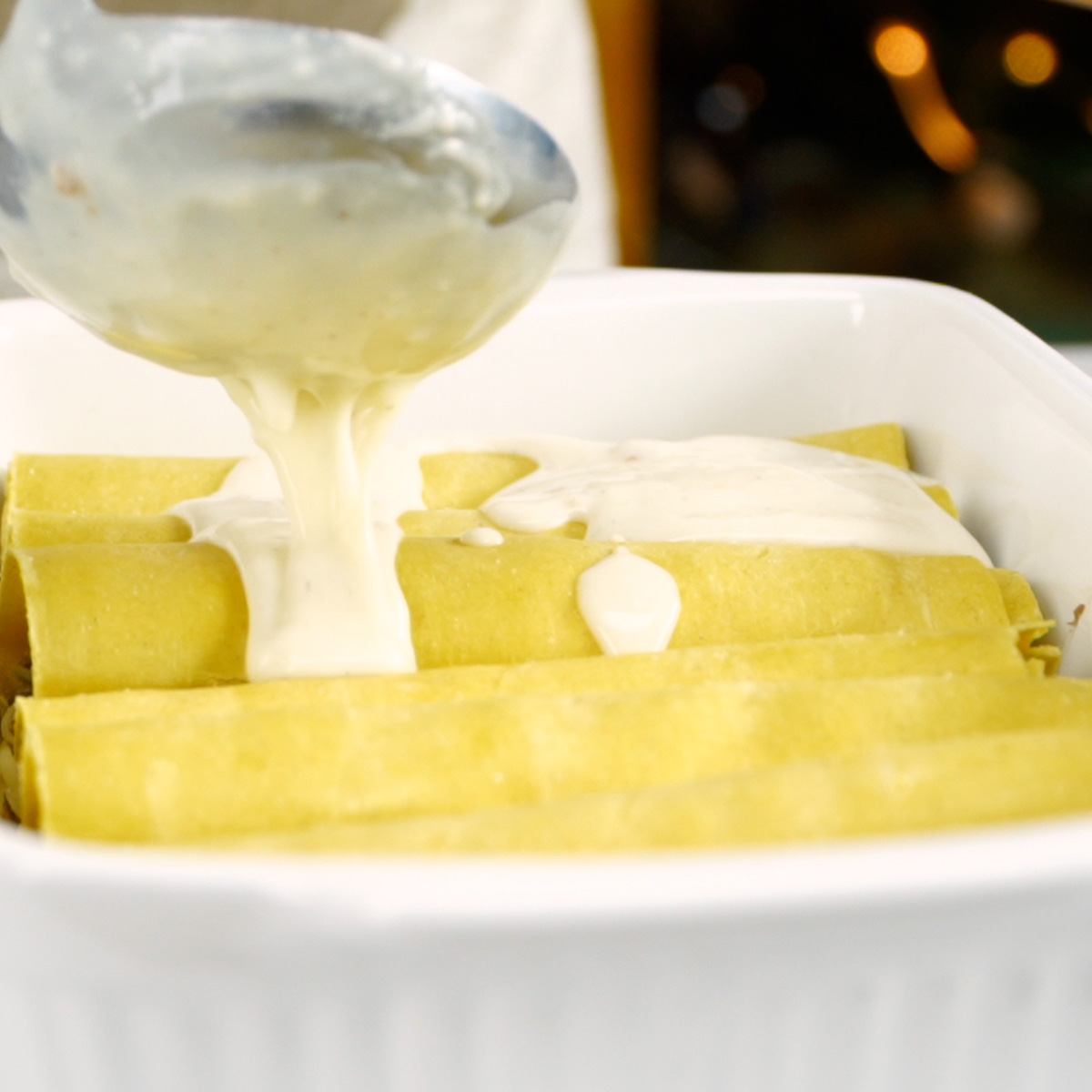 Béchamelsauce wird über die Lasagnerollen gegeben.