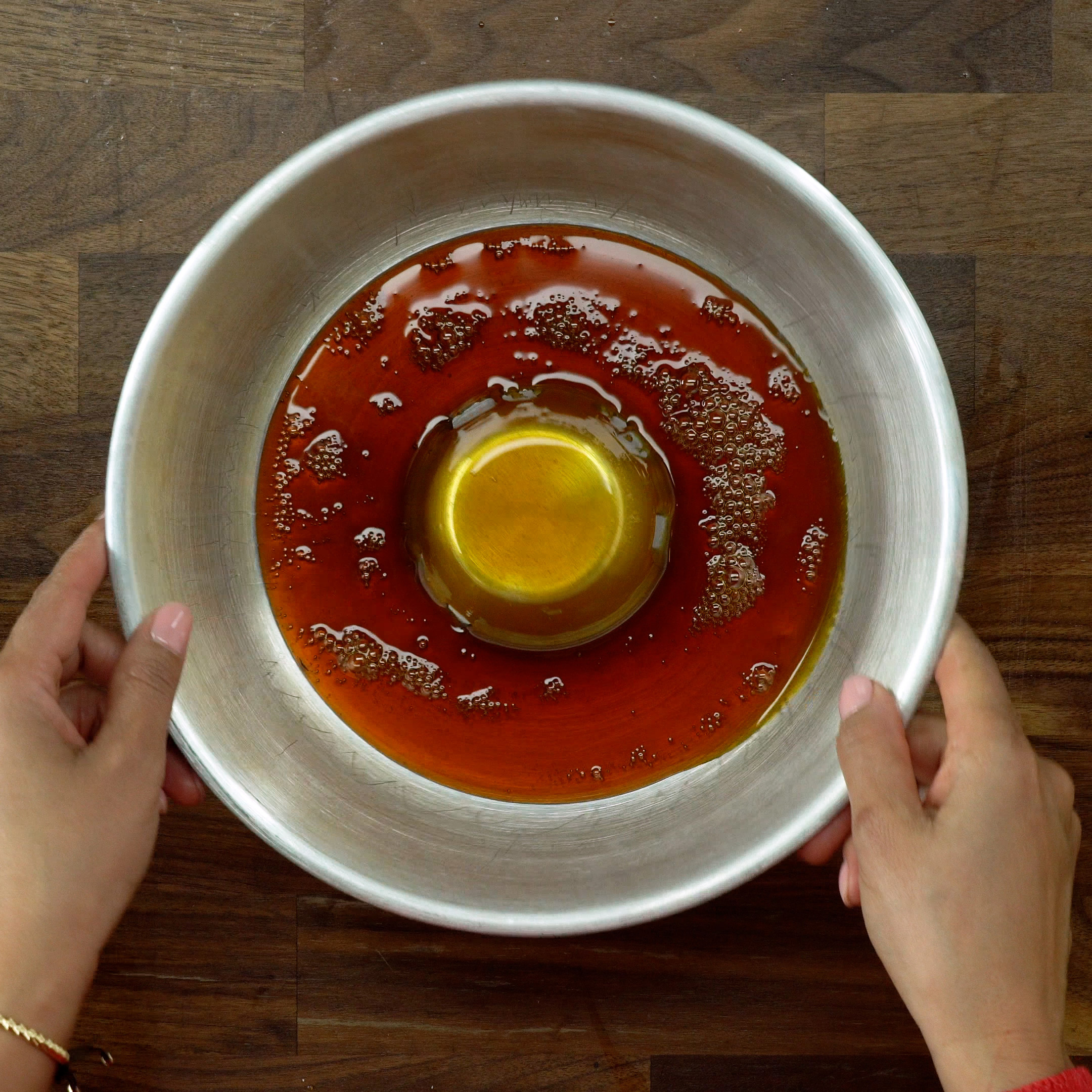 Karamellsauce wird in einer Puddingform verteilt.