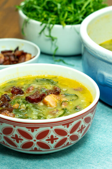 Caldo Verde in einer Schüssel mit Speck und Chouriço serviert.
