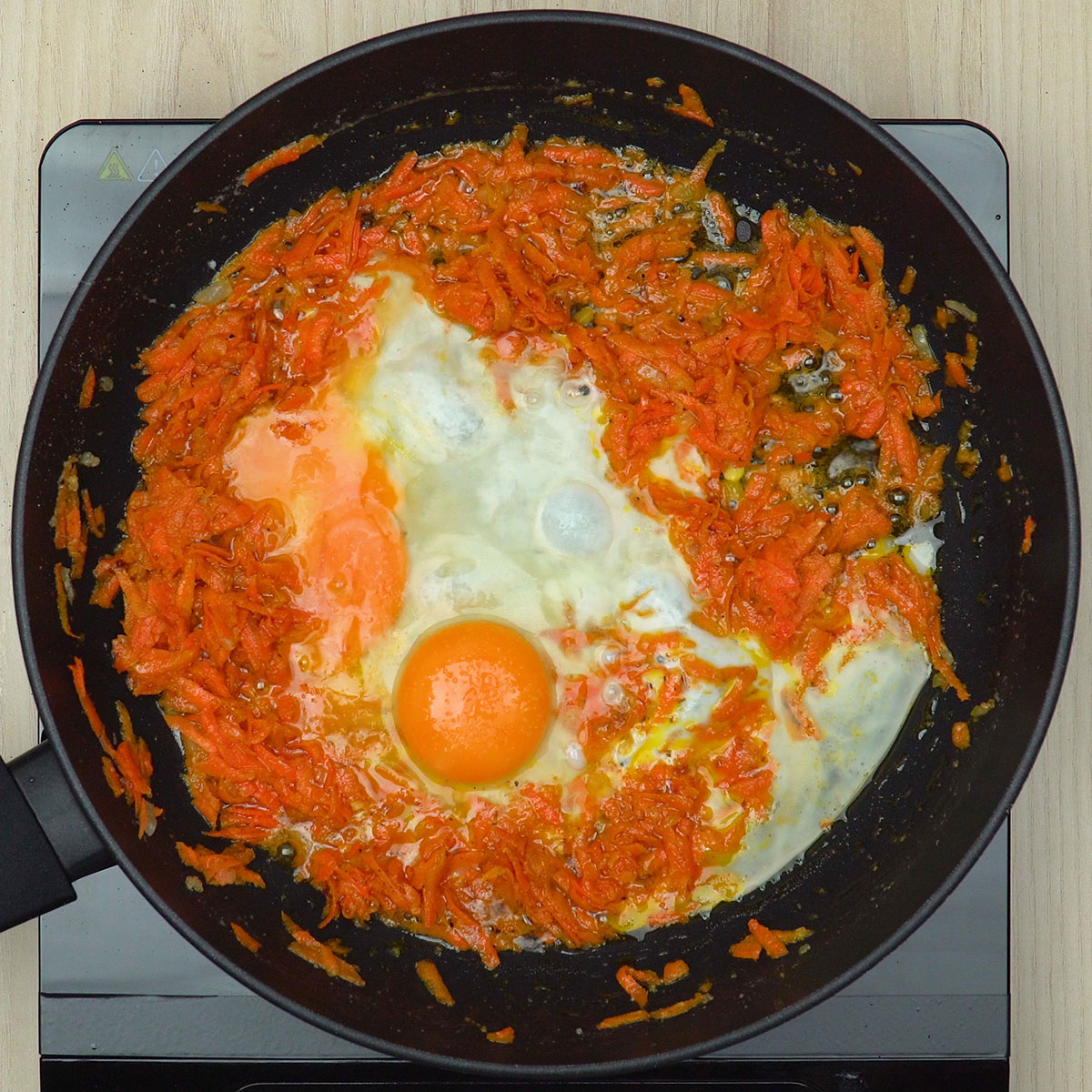 Eier werden mit den Karotten in der Pfanne verrührt.