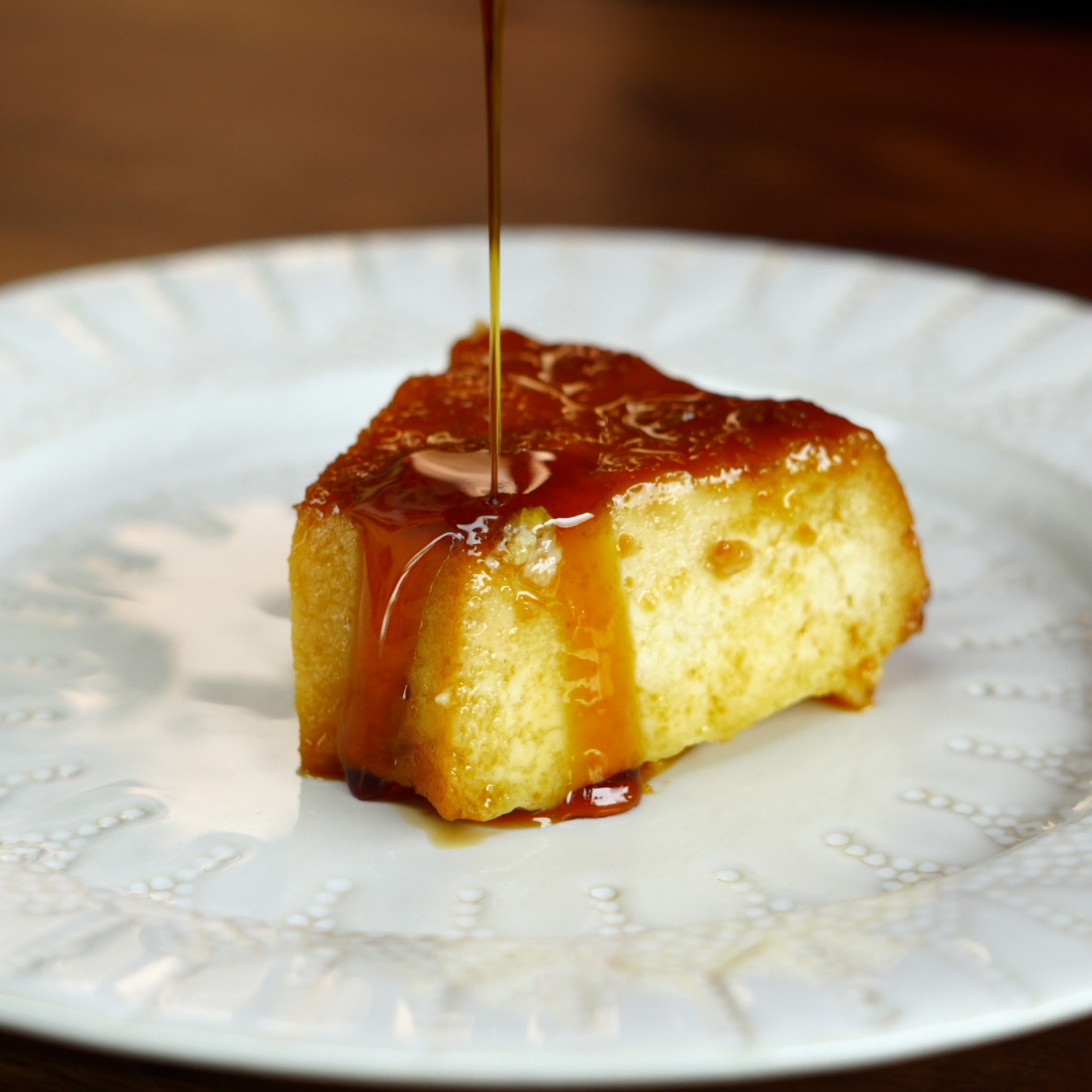 Fertiger Brotpudding mit Kondensmilch und glänzender Karamellsauce.