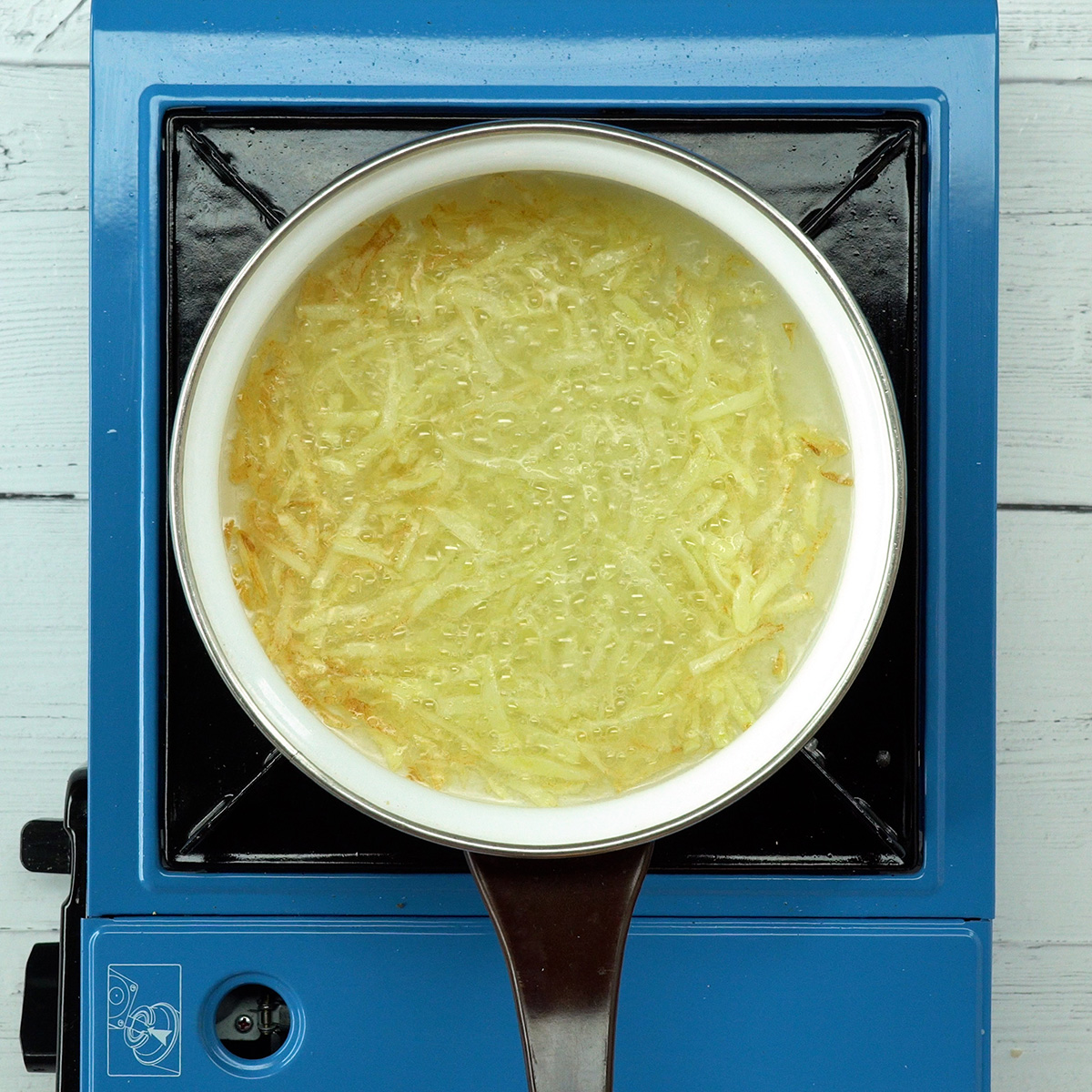 Geriebene Kartoffeln werden für knusprige Kartoffelstreifen frittiert.