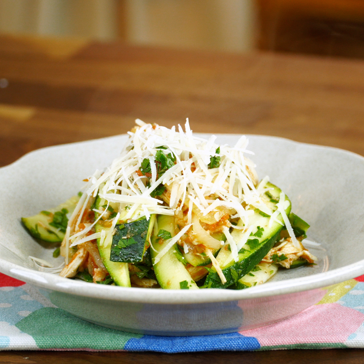 Hähnchen Zucchini Pfanne wird mit geriebenem Parmesan fertiggestellt.