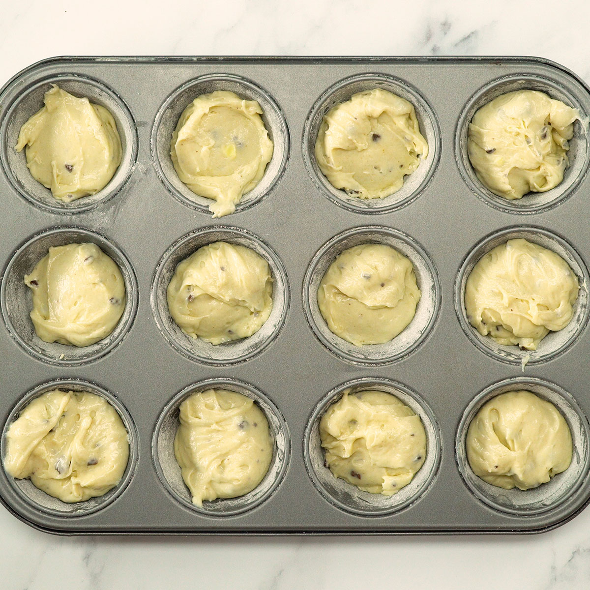 Muffinteig wird vor dem Backen in die Förmchen gefüllt.