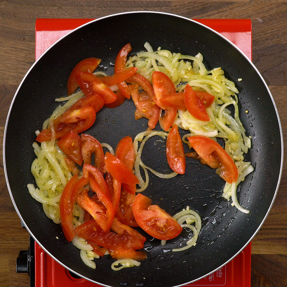 Knoblauch und Tomate werden in der Pfanne angebraten.