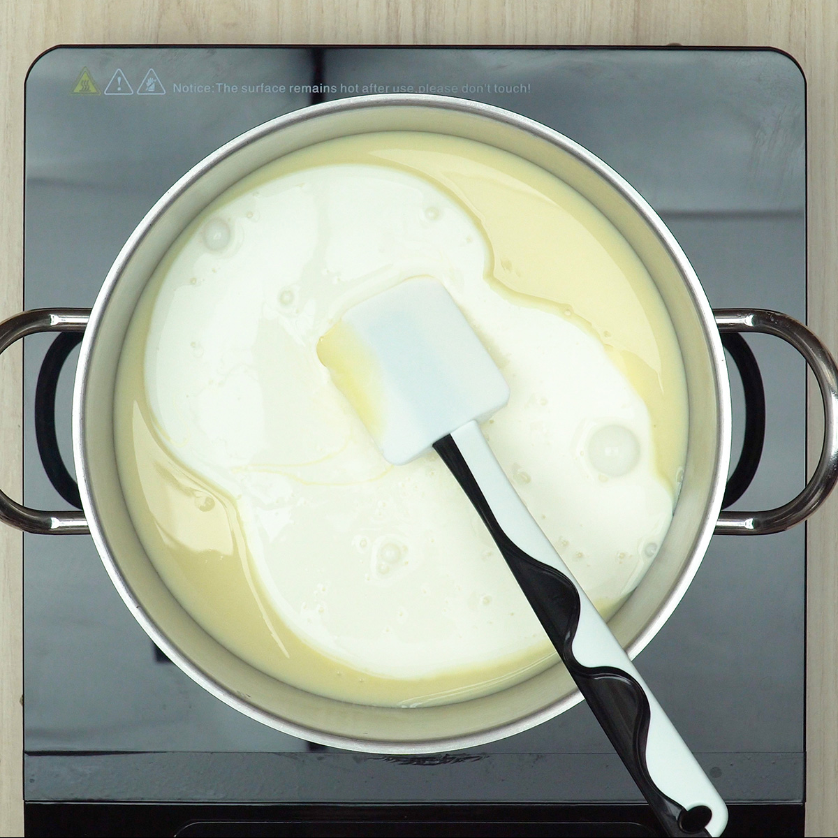 Gezuckerte Kondensmilch, Sahne und Vanille werden im Topf verrührt.