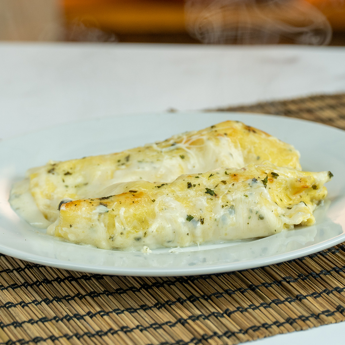 Portion gerollte Lasagne mit Hackfleisch auf dem Teller.