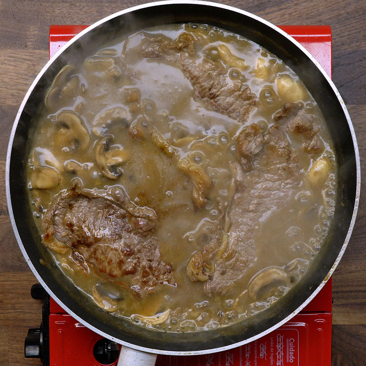 Rindersteaks werden in die Madeira-Sauce gelegt.