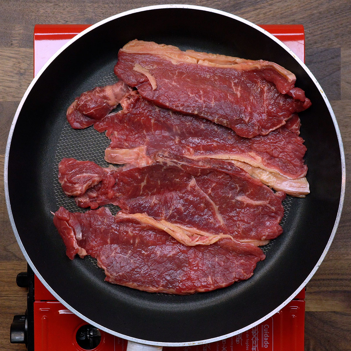 Rindersteaks werden in einer heißen Pfanne angebraten.