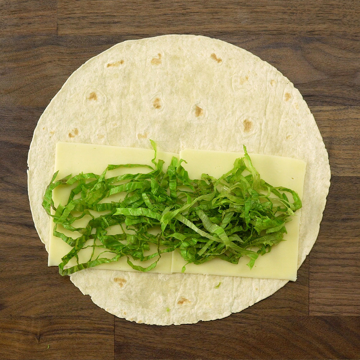 Geschnittener Salat wird auf den Wrap-Fladen gelegt.
