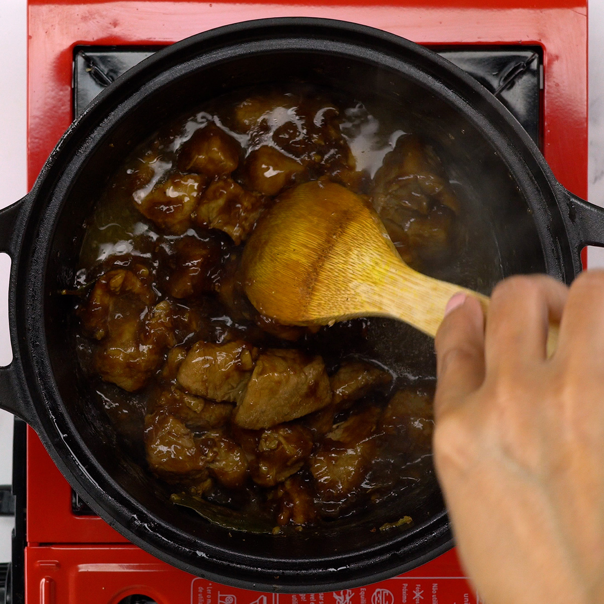 Die Schwarzbiersauce bindet und umhüllt die Schweinewürfel im Topf.
