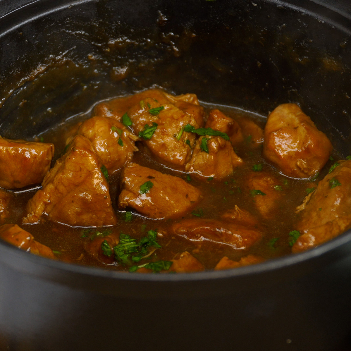 Fertig gegarte Schweinewürfel in dunkler Schwarzbiersauce.
