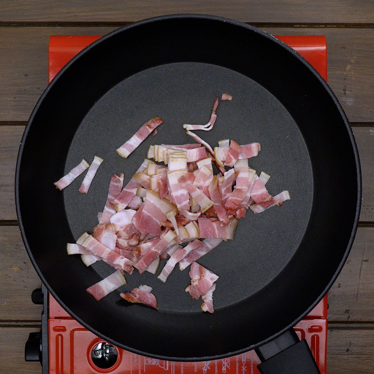 Bacon brät langsam in einer heißen Pfanne, bis er knusprig wird.