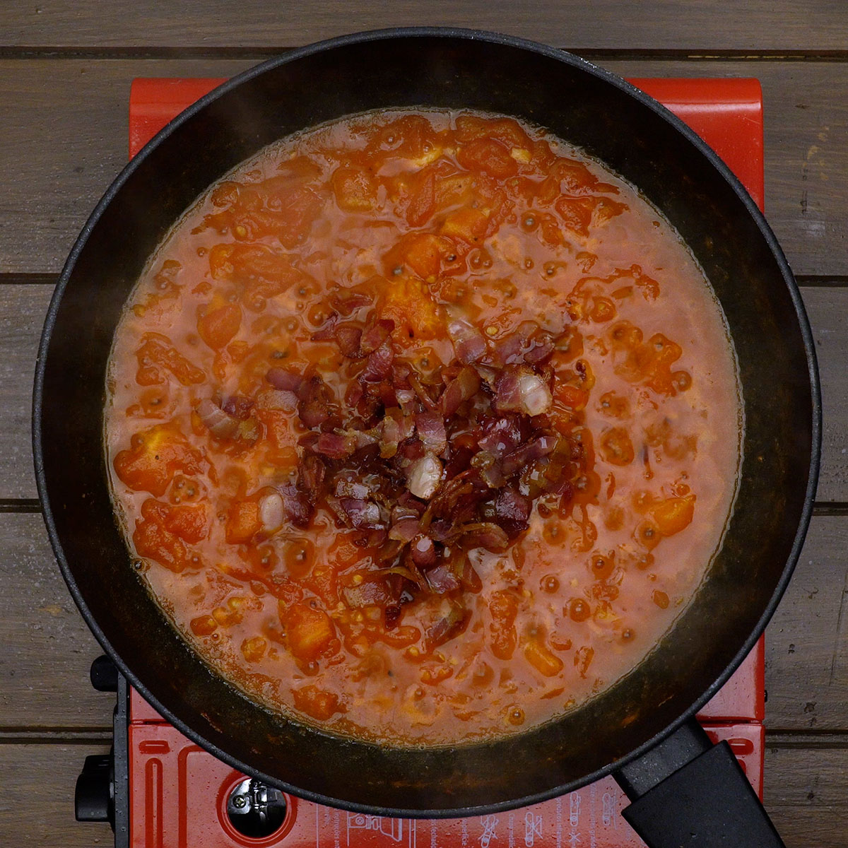 Bacon wird mit der Tomatensauce für Spaghetti Amatriciana vermischt.
