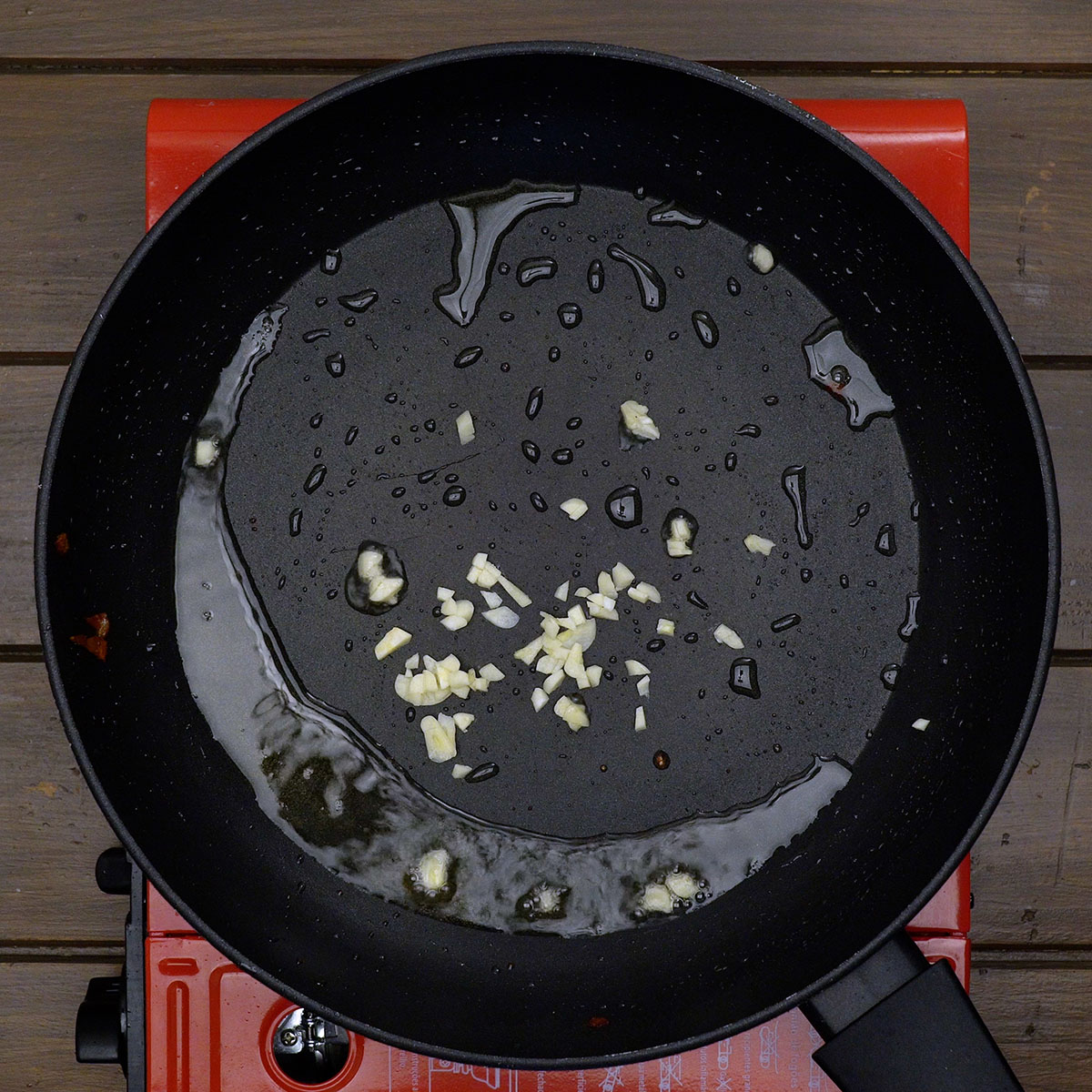 Gehackter Knoblauch wird im Fett vom Bacon für die Amatriciana Sauce angeschwitzt.