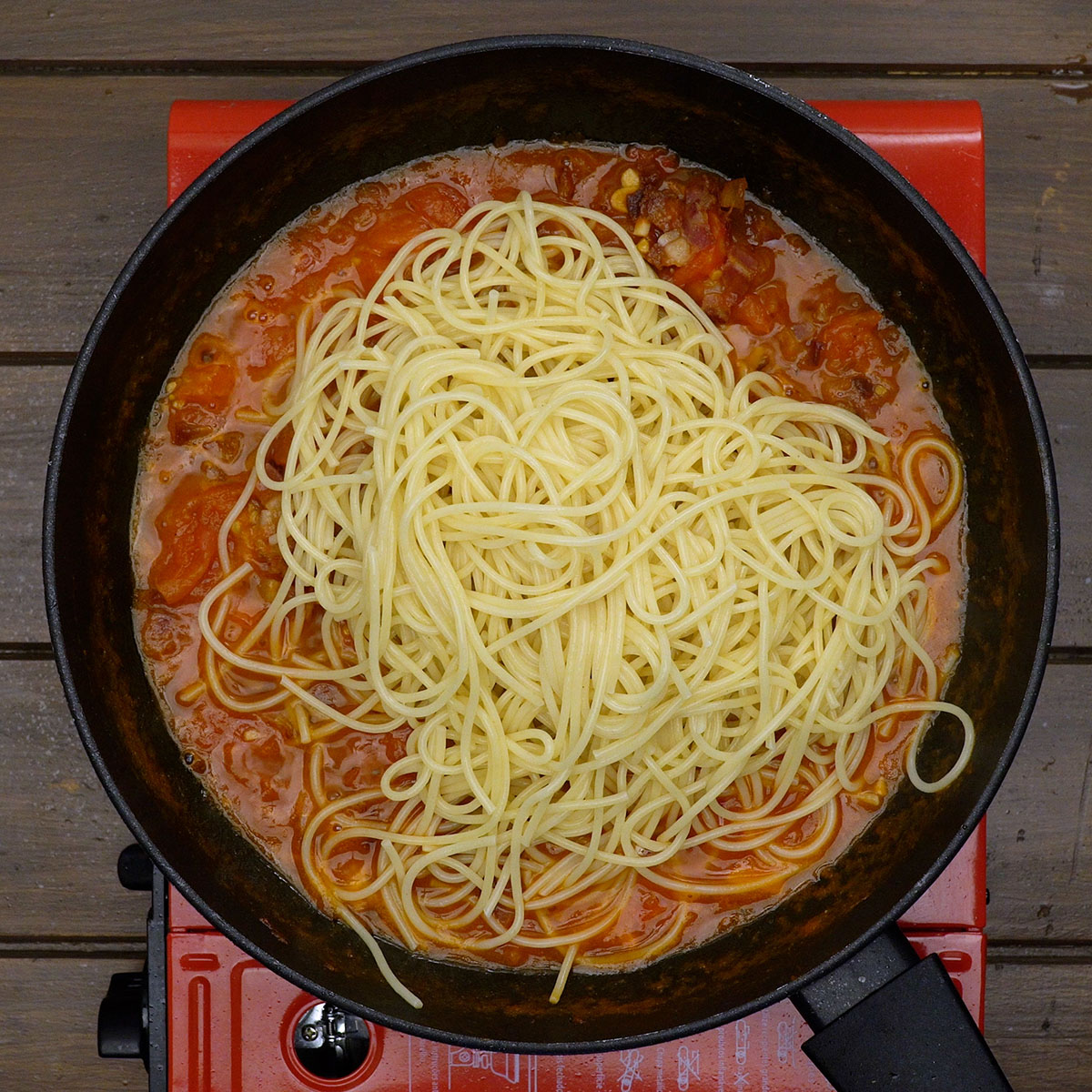 Spaghetti werden in der Pfanne mit der Amatriciana Sauce vermischt.
