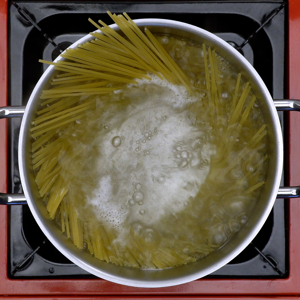 Spaghetti kochen in einem großen Topf mit sprudelndem Wasser.