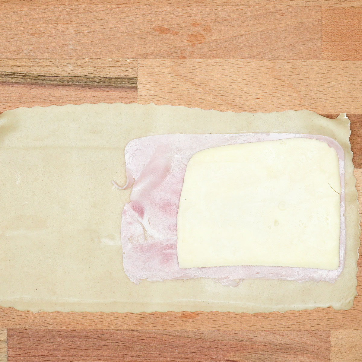 Teigstücke sind mit Kochschinken und Käse belegt.