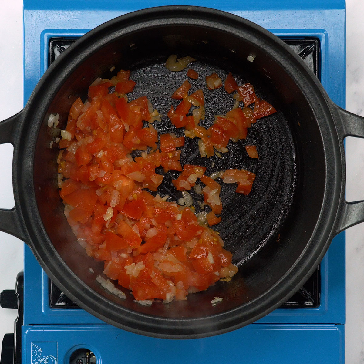 Zwiebel, Knoblauch, Tomate und Paprika werden in Olivenöl angedünstet.